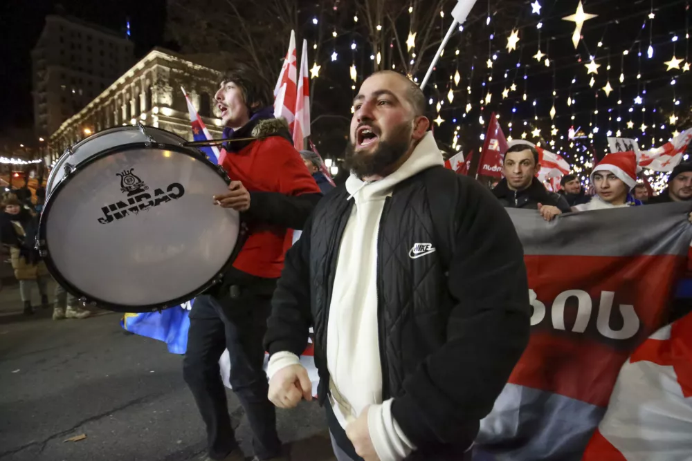 Demonstrators with Georgian national and EU flags march during an anti-government rally outside the Parliament building in Tbilisi, Georgia, on Saturday, Dec. 28, 2024. (AP Photo/Zurab Tsertsvadze)