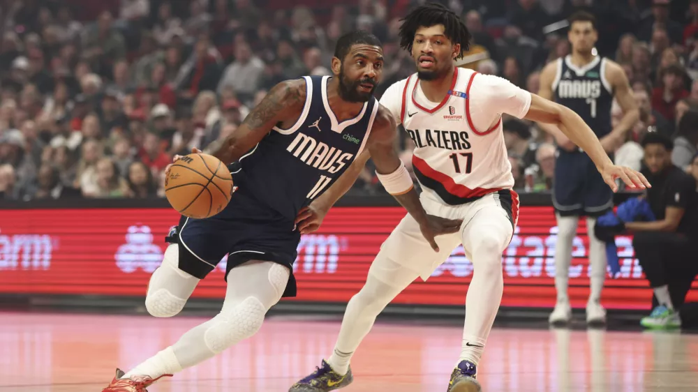 Dallas Mavericks guard Kyrie Irving (11) drives to the basket as Portland Trail Blazers guard Shaedon Sharpe (17) defends during the first half of an NBA basketball game Saturday, Dec. 28, 2024, in Portland, Ore. (AP Photo/Amanda Loman)