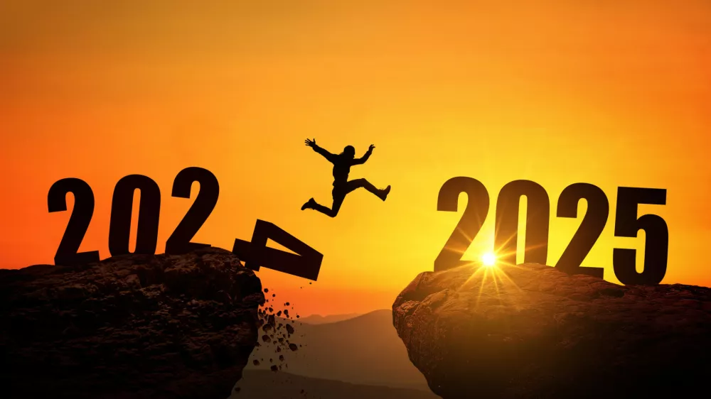 Man jumping on cliff 2025 over the precipice with stones at amazing sunset. New Year's concept. 2024 falls into the abyss. Welcome 2025. People enters the year 2025, creative idea.