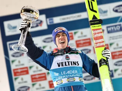 29 December 2024, Bavaria, Oberstdorf: Austria's first placed Stefan Kraft celebrates on the podium with the trophy after the 2nd round of the Men's Large Hill Tournament of the FIS Ski Jumping World Cup. Photo: Daniel Karmann/dpa