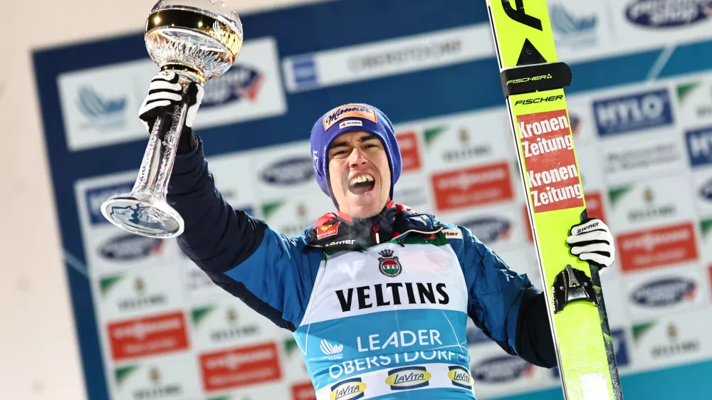 29 December 2024, Bavaria, Oberstdorf: Austria's first placed Stefan Kraft celebrates on the podium with the trophy after the 2nd round of the Men's Large Hill Tournament of the FIS Ski Jumping World Cup. Photo: Daniel Karmann/dpa