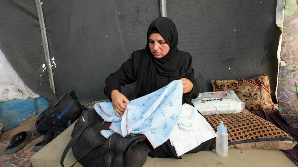 Noura, the mother of Palestinian infant Jumaa Al-Batran, who died of hypothermia after living in a tent with his displaced family, shows his belongings at their tent, in Deir Al-Balah in the central Gaza Strip, December 29, 2024. REUTERS/Ramadan Abed