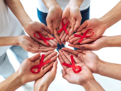 Group of young multiracial woman with red ribbons in hands are struggling against HIV/AIDS. AIDS awareness concept.