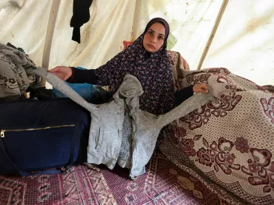 Asmaa, the mother of 9-year-old Palestinian boy Ramadan Hamed, who doctors said died due to malnutrition, shows her son's clothing inside a tent where she shelters after being displaced from her home, in Nusierat in the central Gaza Strip December 7, 2024. REUTERS/Ramadan Abed