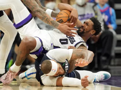 Dec 30, 2024; Sacramento, California, USA; Sacramento Kings guard Malik Monk (0) falls on top of Dallas Mavericks center Daniel Gafford (bottom) during the third quarter at Golden 1 Center. Mandatory Credit: Darren Yamashita-Imagn Images