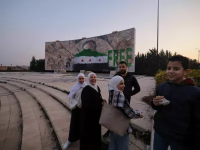 People stand near a graffiti of the Syrian rebels flag painted on a mosaic of former Syrian president Hafez al-Assad after the ousting of President Bashar al-Assad, in Damascus Syria January 2, 2025. REUTERS/Zohra Bensemra   TPX IMAGES OF THE DAY