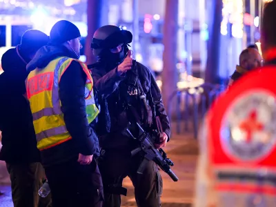 FILED - 20 December 2024, Saxony-Anhalt, Magdeburg: An armed police officer speaks with his colleagues at the the Magdeburg incident scene. The suspect in the deadly car-ramming incident at a Christmas market in the German city of Magdeburg had appeared in seven investigative proceedings in the two years prior to the attack, dpa has learned from security sources. Photo: Heiko Rebsch/dpa