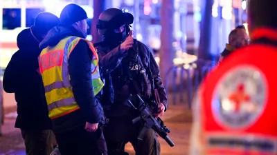 FILED - 20 December 2024, Saxony-Anhalt, Magdeburg: An armed police officer speaks with his colleagues at the the Magdeburg incident scene. The suspect in the deadly car-ramming incident at a Christmas market in the German city of Magdeburg had appeared in seven investigative proceedings in the two years prior to the attack, dpa has learned from security sources. Photo: Heiko Rebsch/dpa