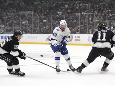 Tampa Bay Lightning defenseman Darren Raddysh, center, passes the puck while under pressure from Los Angeles Kings center Alex Turcotte, left, and center Anze Kopitar during the first period of an NHL hockey game, Saturday, Jan. 4, 2025, in Los Angeles. (AP Photo/Mark J. Terrill)