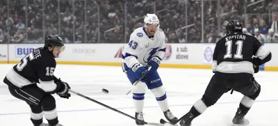 Tampa Bay Lightning defenseman Darren Raddysh, center, passes the puck while under pressure from Los Angeles Kings center Alex Turcotte, left, and center Anze Kopitar during the first period of an NHL hockey game, Saturday, Jan. 4, 2025, in Los Angeles. (AP Photo/Mark J. Terrill)