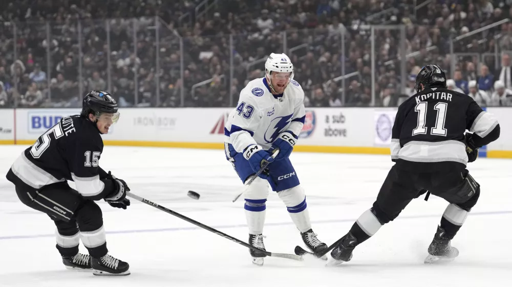 Tampa Bay Lightning defenseman Darren Raddysh, center, passes the puck while under pressure from Los Angeles Kings center Alex Turcotte, left, and center Anze Kopitar during the first period of an NHL hockey game, Saturday, Jan. 4, 2025, in Los Angeles. (AP Photo/Mark J. Terrill)