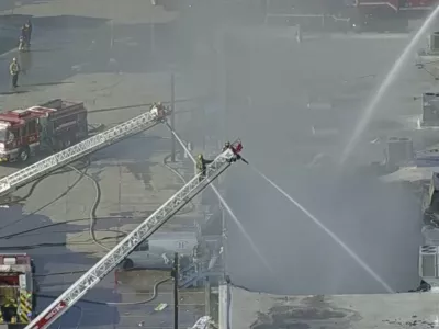 In this image from video provided by KDFW FOX 4, firefighters spray water on the Plaza Latina shopping center in Dallas, Texas on Friday, Jan. 3, 2025. (KDFW FOX 4 via AP)