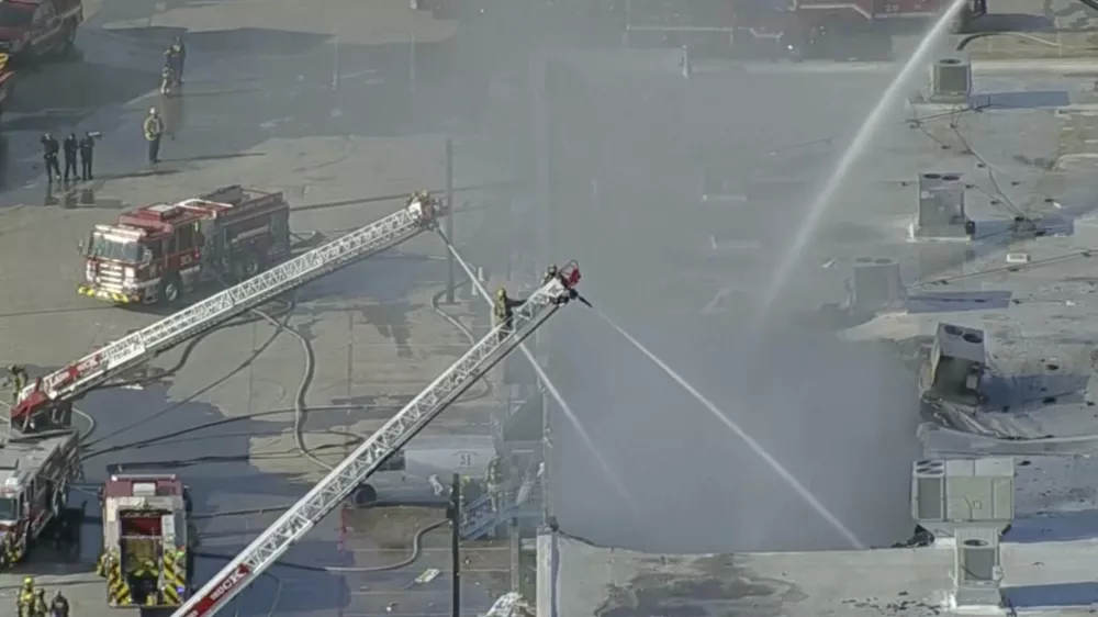 In this image from video provided by KDFW FOX 4, firefighters spray water on the Plaza Latina shopping center in Dallas, Texas on Friday, Jan. 3, 2025. (KDFW FOX 4 via AP)