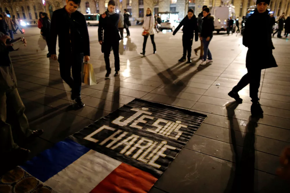 FILE PHOTO: People gather on the Place de la Republique square to pay tribute to the victims of last year's shooting at the French satirical newspaper Charlie Hebdo, in Paris, France, January 7, 2016. France this week commemorates the victims of last year's Islamist militant attacks on satirical weekly Charlie Hebdo and a Jewish supermarket with eulogies, memorial plaques and another cartoon lampooning religion. REUTERS/Stephane Mahe/File Photo