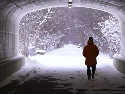 A pedestrian makes their way though a tunnel along the snow-covered Monon Trail in Carmel, Ind., Monday, Jan. 6, 2025. (AP Photo/Michael Conroy)