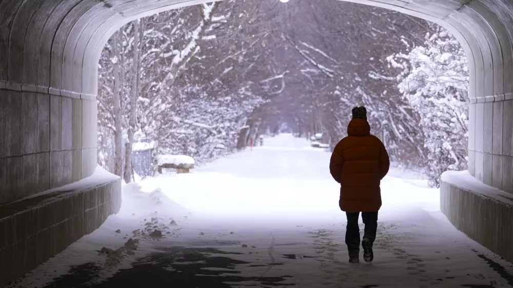 A pedestrian makes their way though a tunnel along the snow-covered Monon Trail in Carmel, Ind., Monday, Jan. 6, 2025. (AP Photo/Michael Conroy)