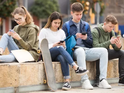 Four teenagers chatting on their smartphone on walking