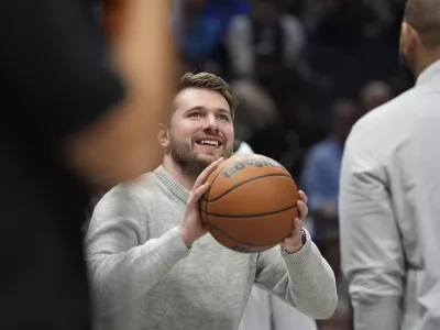 Injured Dallas Mavericks guard Luka Doncic plays with the game ball during a timeout in the first half of an NBA basketball game against the Los Angeles Lakers, Tuesday, Jan. 7, 2025, in Dallas. (AP Photo/LM Otero)