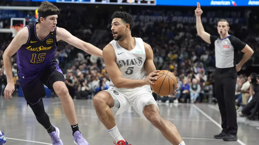 Dallas Mavericks guard Quentin Grimes (5) moves the ball against Los Angeles Lakers guard Austin Reaves (15) during the first half of an NBA basketball game Tuesday, Jan. 7, 2025, in Dallas. (AP Photo/LM Otero)