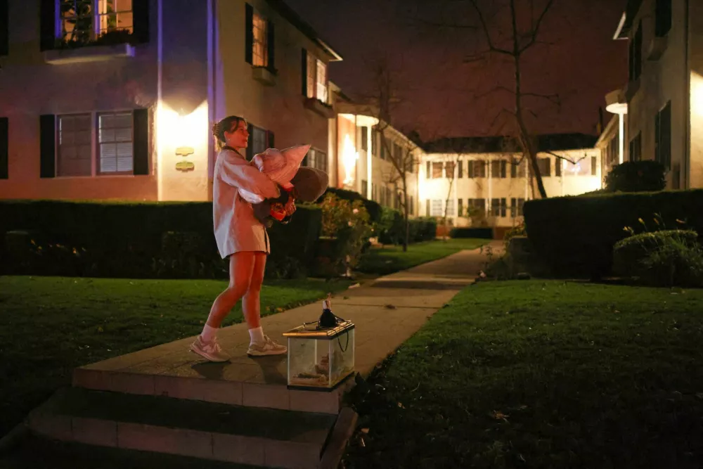 A woman waits to leave following an evacuation order, as a wildfire burns in the Pacific Palisades neighborhood of west Los Angeles, in Santa Monica, California, U.S., January 7, 2025. REUTERS/Daniel Cole  REFILE - QUALITY REPEAT