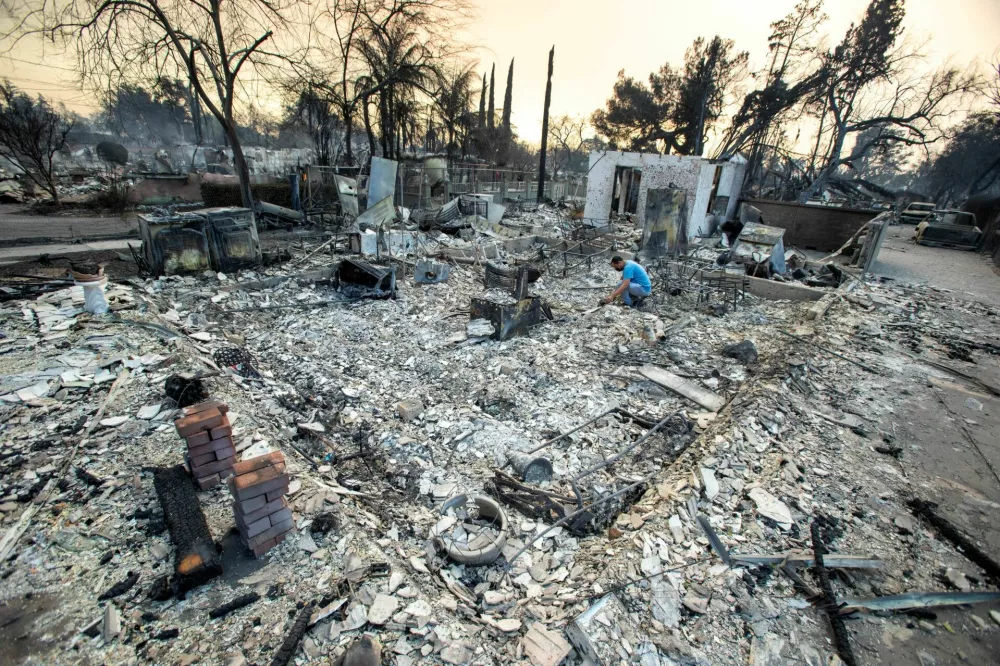 A man looks for belongings in the remains of his home after burned down by wildfires in the Los Angeles area, at the Eaton Fire in Altadena, California, U.S. January 9, 2025. REUTERS/Ringo Chiu