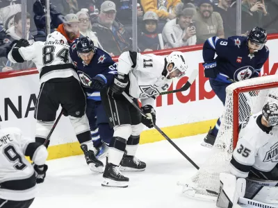 Los Angeles Kings' Vladislav Gavrikov (84) and Anze Kopitar (11) defend against Winnipeg Jets' Nino Niederreiter (62) during first-period NHL hockey game action in Winnipeg, Manitoba, Friday, Jan. 10, 2025. (John Woods/The Canadian Press via AP)