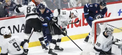 Los Angeles Kings' Vladislav Gavrikov (84) and Anze Kopitar (11) defend against Winnipeg Jets' Nino Niederreiter (62) during first-period NHL hockey game action in Winnipeg, Manitoba, Friday, Jan. 10, 2025. (John Woods/The Canadian Press via AP)