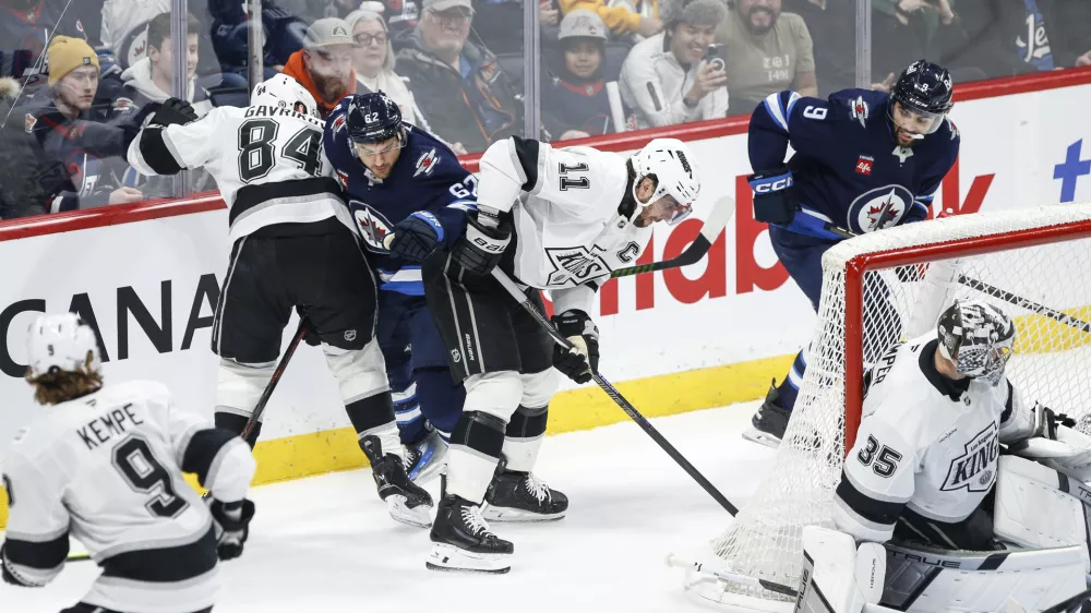 Los Angeles Kings' Vladislav Gavrikov (84) and Anze Kopitar (11) defend against Winnipeg Jets' Nino Niederreiter (62) during first-period NHL hockey game action in Winnipeg, Manitoba, Friday, Jan. 10, 2025. (John Woods/The Canadian Press via AP)