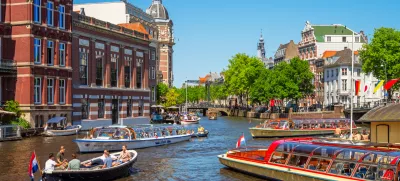 Amsterdam, Netherlands - June 3, 2023: Canal in Amsterdam, Netherlands busy with boat traffic on sunny saturday afternoon in June.