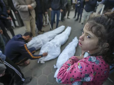 A girl watches as Mohammad Eid mourns his cousin Dima, along with her uncle and grandfather, who were killed in an Israeli airstrike on Saturday, during their funeral in Deir al-Balah, central Gaza Strip, Sunday, Jan. 12, 2025. (AP Photo/Abdel Kareem Hana)