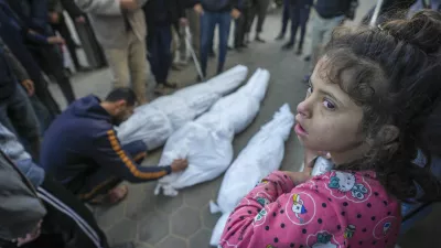 A girl watches as Mohammad Eid mourns his cousin Dima, along with her uncle and grandfather, who were killed in an Israeli airstrike on Saturday, during their funeral in Deir al-Balah, central Gaza Strip, Sunday, Jan. 12, 2025. (AP Photo/Abdel Kareem Hana)