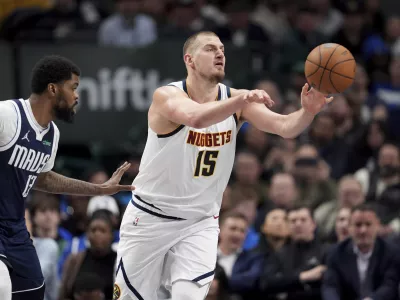 Denver Nuggets center Nikola Jokic makes a pass under pressure from Dallas Mavericks forward Naji Marshall (13) in the second half of an NBA basketball game in Dallas, Tuesday, Jan. 14, 2025. (AP Photo/Tony Gutierrez)