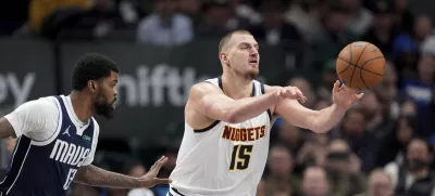 Denver Nuggets center Nikola Jokic makes a pass under pressure from Dallas Mavericks forward Naji Marshall (13) in the second half of an NBA basketball game in Dallas, Tuesday, Jan. 14, 2025. (AP Photo/Tony Gutierrez)