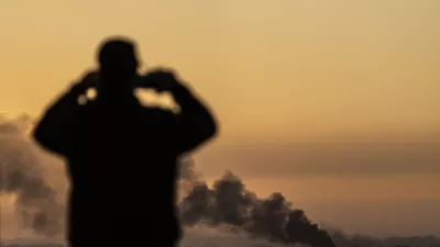 FILE - A man looks at smoke rising following an explosion inside the Gaza Strip, from an observation point in Sderot, southern Israel, on Jan. 13, 2025. (AP Photo/Ariel Schalit, File)