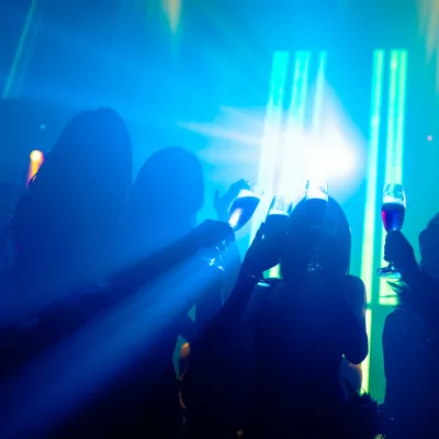 Silhouette image of people dance in disco night club to music from DJ on stage. New year night party and nightlife concept.