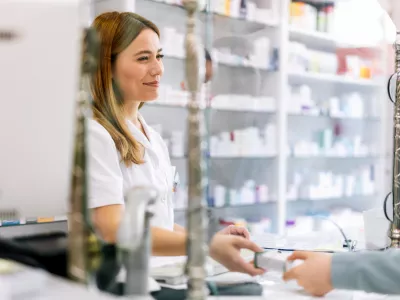 Woman pharmacist consulting customer at counter for prescription drugs or medicine at the pharmacy. Female doctor giving patient medical antibiotics at the pharmacy / Foto: Jovanmandic