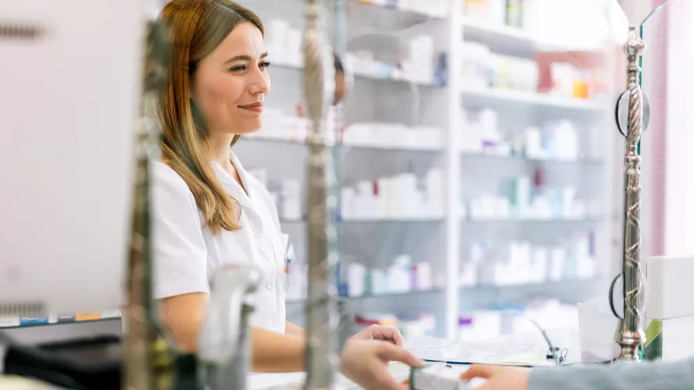 Woman pharmacist consulting customer at counter for prescription drugs or medicine at the pharmacy. Female doctor giving patient medical antibiotics at the pharmacy / Foto: Jovanmandic