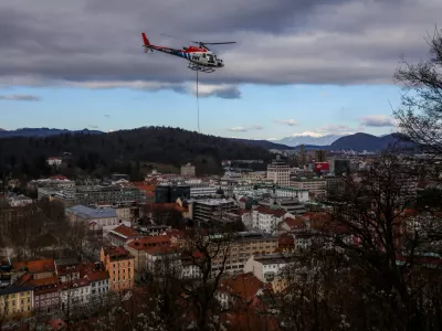 - Helikopter z privezanim drevesom in potniško letalo,- drevo v zraku, leteče drevo,- 13.01.2024. - Sečnja in spravilo oslabljenega lesa na Grajskem hribu v Ljubljani tudi s helikopterjem prvič v Sloveniji.//FOTO: Bojan Velikonja