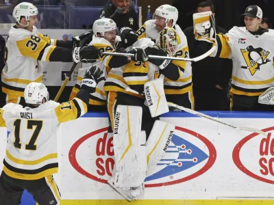 Pittsburgh Penguins goaltender Alex Nedeljkovic, center, celebrates with teammates after scoring during the third period of an NHL hockey game against the Buffalo Sabres, Friday, Jan. 17, 2025, in Buffalo, N.Y. (AP Photo/Jeffrey T. Barnes)