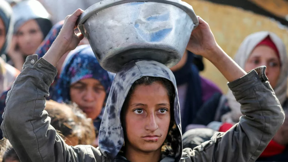 Palestinians gather to receive food cooked by a charity kitchen, before a ceasefire between Hamas and Israel takes effect, in Khan Younis, in the southern Gaza Strip, January 17, 2025. REUTERS/Hatem Khaled   TPX IMAGES OF THE DAY