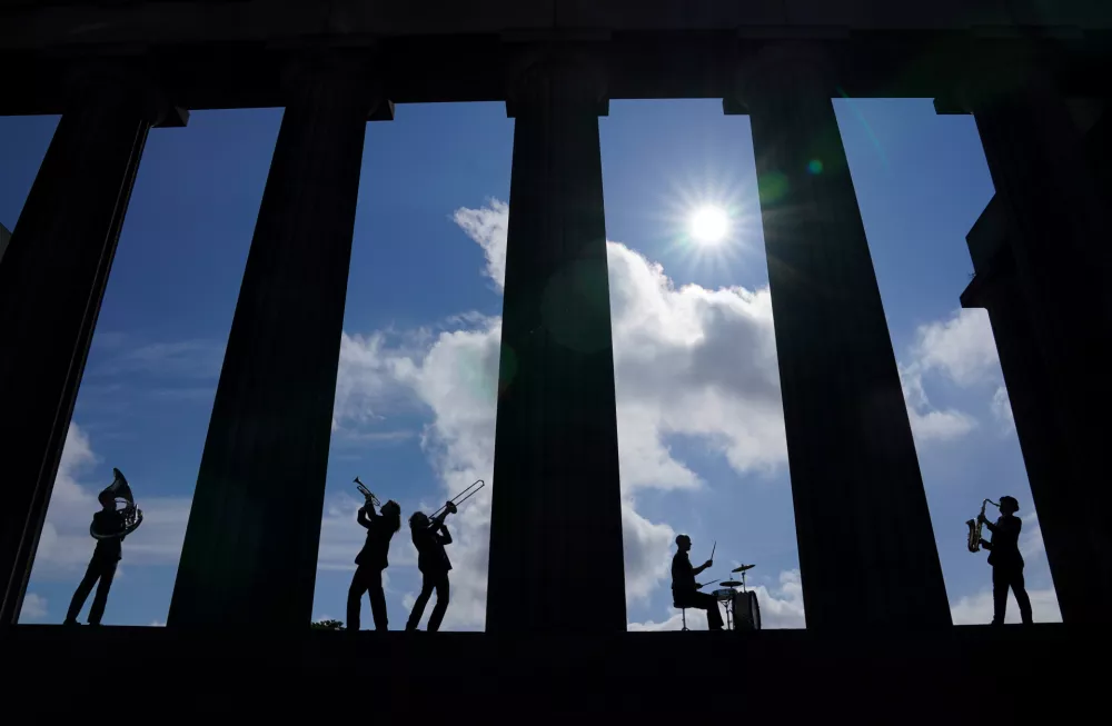 ﻿08 July 2021, United Kingdom, Edinburgh: Members of the band Brass Gumbo, Charles Dearness (Trumpet), Tom Pickles (Saxophone), Ross Lothian (Trombone) Rory Clark (Sousaphone) and Jamie Graham (Drums), play brass instruments in between the columns of the National Monument on Calton Hill in Edinburgh during a photocall for the Edinburgh Jazz and Blues Festival 2021. Photo: Andrew Milligan/PA Wire/dpa