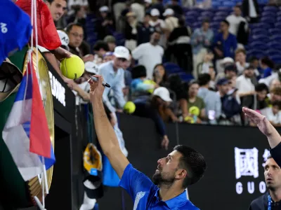 Novak Djokovic of Serbia signs autographs after his quarterfinal match against Carlos Alcaraz of Spain at the Australian Open tennis championship in Melbourne, Australia, Wednesday, Jan. 22, 2025. (AP Photo/Vincent Thian)