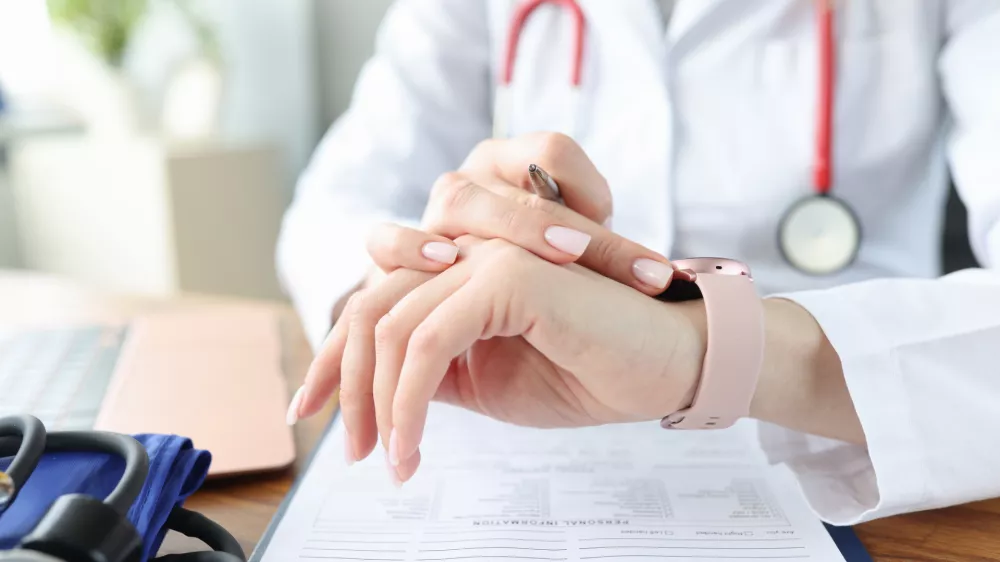 Doctor looks at clock at work table in medical office. Irregular working hours for health workers concept