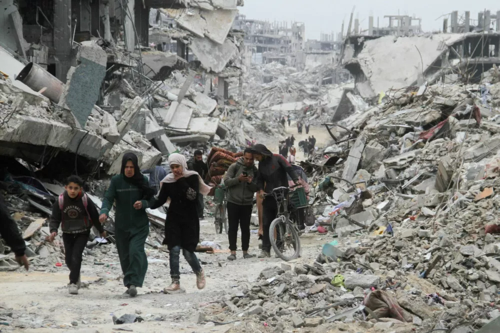 Palestinians walk past the rubble of buildings and houses destroyed during the Israeli offensive, amid a ceasefire between Israel and Hamas, in Jabalia in the northern Gaza Strip, January 22, 2025. REUTERS/Mahmoud Issa