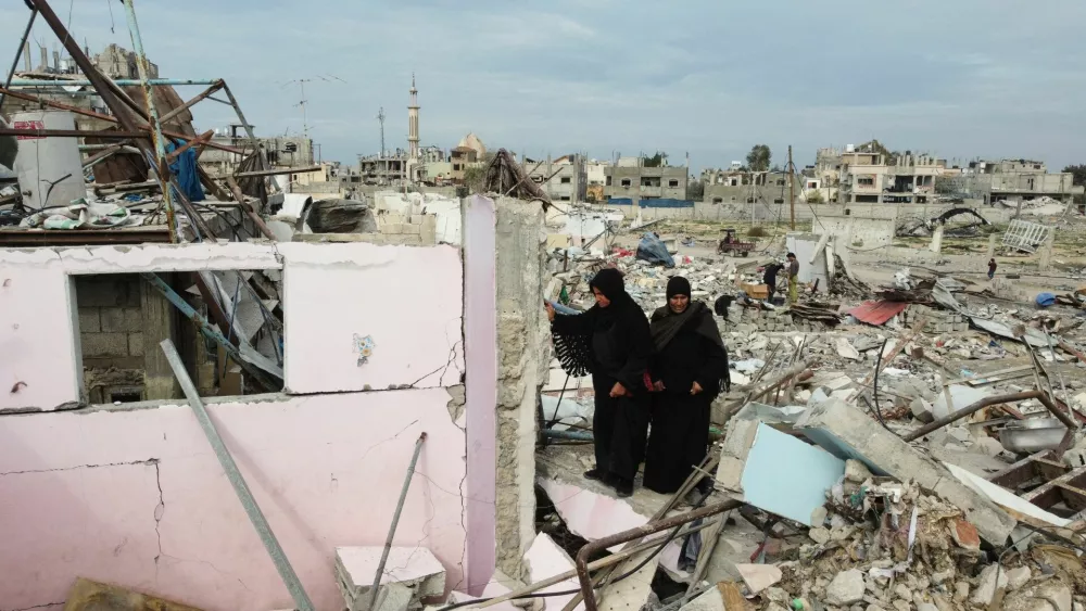 A drone view shows Palestinian women walking amid the rubble of destroyed houses and buildings, following a ceasefire between Israel and Hamas, in Rafah in the southern Gaza Strip, January 22, 2025. REUTERS/Mohammed Salem