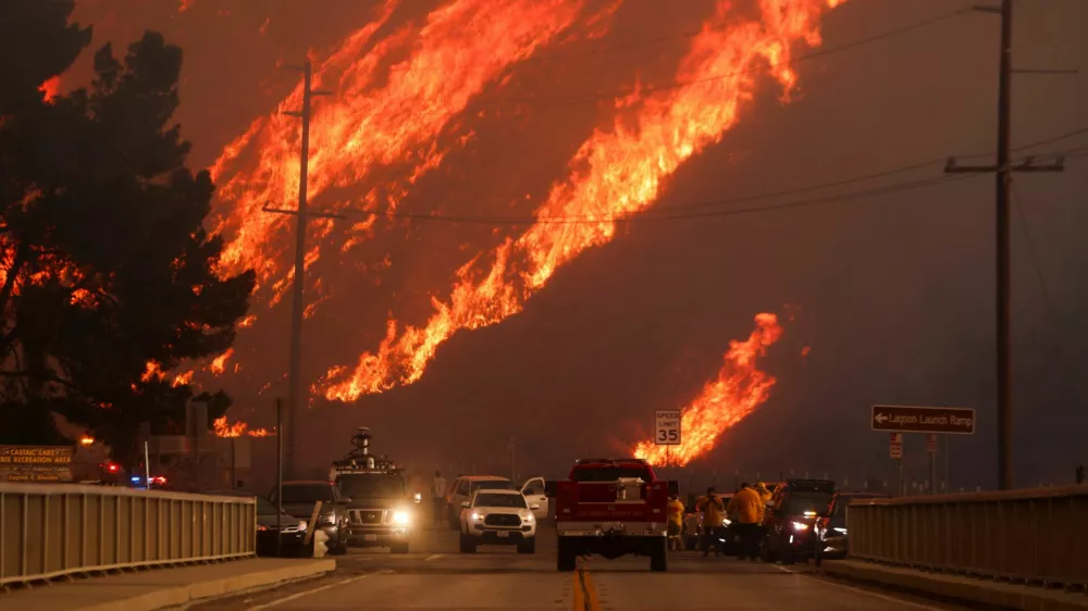 Flames rise behind vehicles as the Hughes Fire burns in Castaic Lake, California, U.S. January 22, 2025. REUTERS/David Swanson   TPX IMAGES OF THE DAY