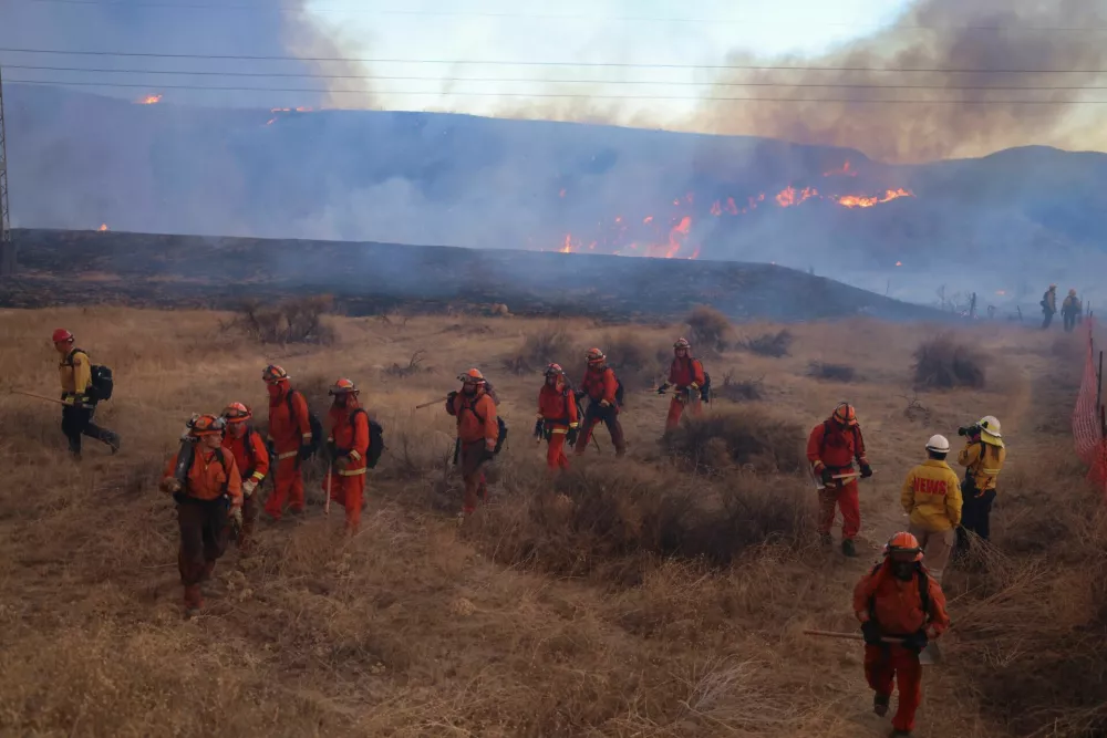 Firefighters, along with California Department of Corrections and Rehabilitation prisoners who are part of the firefighting crew, work as the Hughes Fire burns in Castaic Lake, California, U.S. January 22, 2025. REUTERS/David Swanson