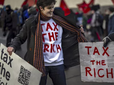 Activist Marlene Engelhorn holds banners during a protest at the Meeting of World Economic Forum in Davos, Switzerland, Thursday, Jan. 23, 2025. (Michael Buholzer/Keystone via AP)