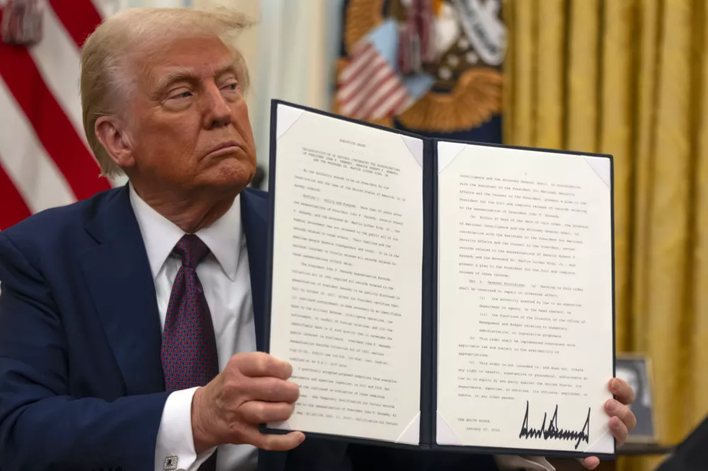 President Donald Trump holds up a signed executive order aiming to declassify remaining federal records relating to the assassinations of President John F. Kennedy, Sen. Robert F. Kennedy, and Martin Luther King Jr., in the Oval Office of the White House, Thursday, Jan. 23, 2025, in Washington. (AP Photo/Ben Curtis)