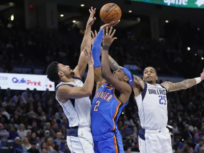 Oklahoma City Thunder guard Shai Gilgeous-Alexander (2) looks to shoot between Dallas Mavericks guard Quentin Grimes, left, and forward P.J. Washington (25) during the second half of an NBA basketball game Thursday, Jan. 23, 2025, in Oklahoma City. (AP Photo/Nate Billings)